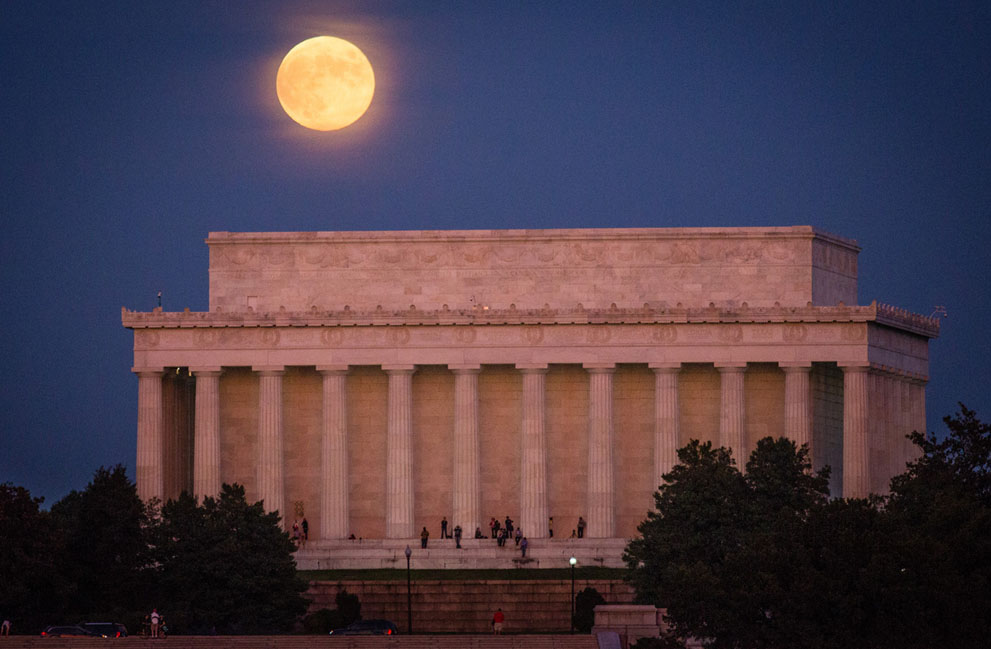 Người dân ngắm hoàng hôn từ nhà tưởng niệm Lincoln, ở Washington, D.C., khi mặt trăng tròn mọc phía sau, 18/10/2013.
