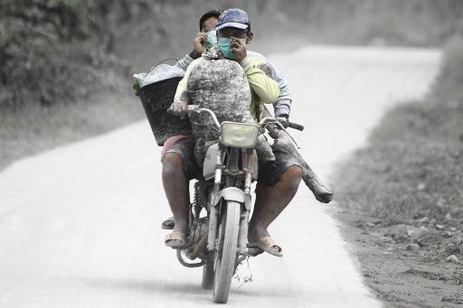Các cư dân của đảo Sumatra đi trên một con đường phủ đầy tro sau khi đợt phun trào của núi lửa Sinabung ở phía bắc hòn đảo của Indonesia