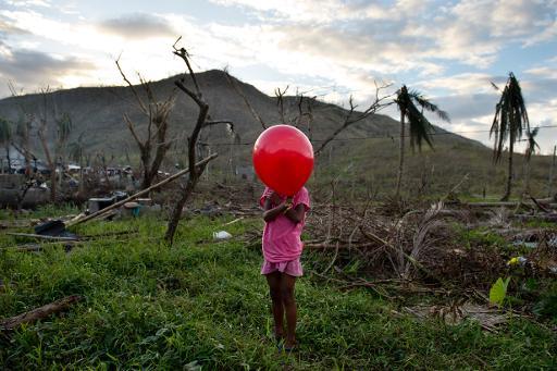 Một cô bé chơi với một quả bóng trong đống đổ nát của ngôi nhà bị phá hủy bởi cơn bão Haiyan, Philippines