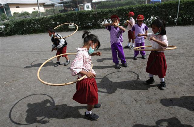 Các em học sinh đeo khẩu trang khu chơi lắc vòng tại một trường tiểu học ở Sukandebi, Bắc Sumatra