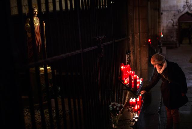 Một phụ nữ thắp nến trước tượng Chúa Giêsu bên trong nhà thờ Barcelona, Tây Ban Nha, 28112013