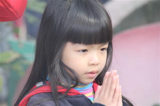 Một cô bé đang chắp tay trước cửa chùa