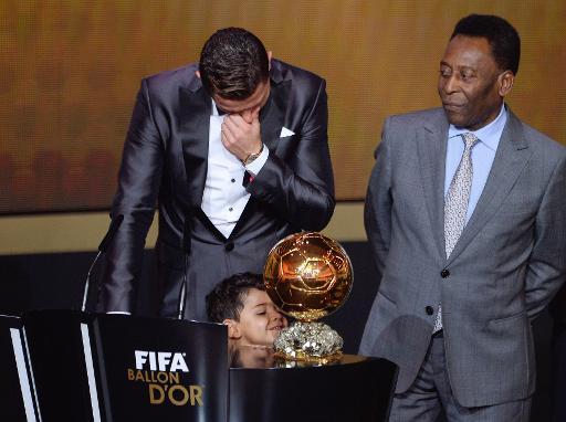 Cầu thủ Cristiano Ronaldo, đã giành được Quả bóng vàng, lau nước mắt trước ánh mắt của Pele, với cậu con trai của mình ở phía trước của danh hiệu