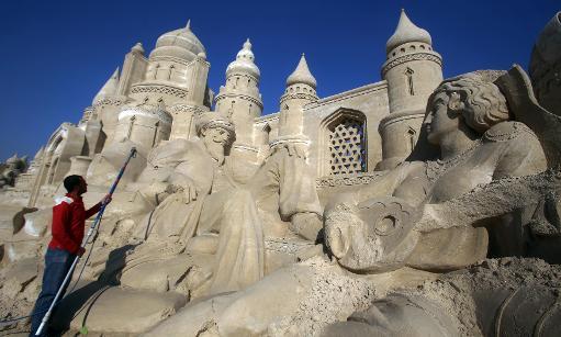 Một người đàn ông xây dựng một lâu đài cát trong một ngôi làng cát tại Kuwait City. (Cô-oét)