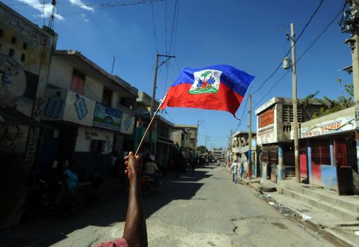 Một người đàn ông nắm giữ một lá cờ Haiti trong một cuộc biểu tình chống lại Tổng thống Michel Martelly tại Port-au-Prince