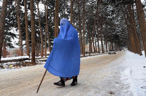 Một người phụ nữ mặc mốt mới nhất với mạng che mặt đầy đủ trong một đường phố tuyết ở Herat, Afghanistan