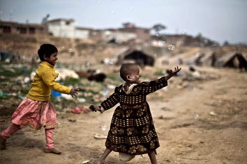 Hai bé gái Pakistan đuổi theo những quả bong bóng tại một khu ổ chuột ở Rawalpindi.
