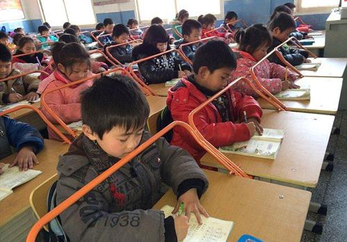 Một trường tiểu học ở Trung Quốc quyết định lắp khung thép cho bàn học để học sinh ngồi đúng tư thế và phòng tránh cận thị học đường.