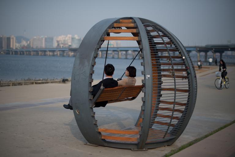 Một cặp đôi ngồi trong chiếc đu công cộng ở bờ sông Hàn - Hàn Quốc