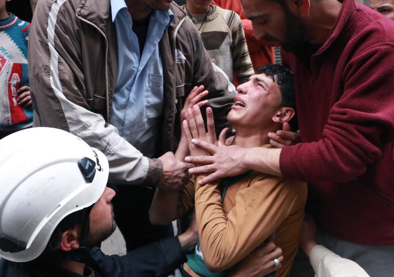 Một người đàn ông được an ủi bởi nhân viên cứu hộ sau một cuộc đụng độ giữa quân đội Syria và quân nổi dậy ở Aleppo