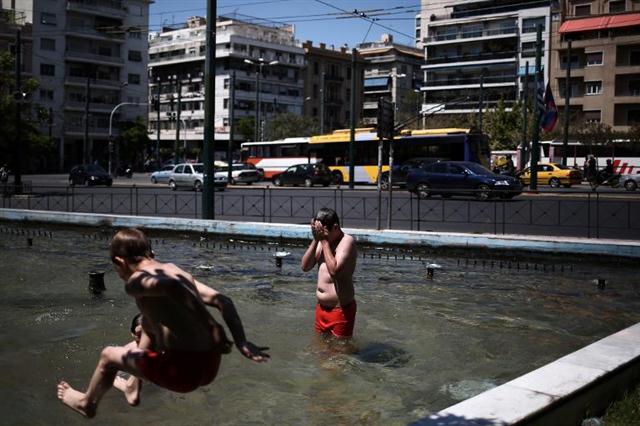 Những đứa trẻ tắm trong một đài phun nước ở trung tâm của Athens