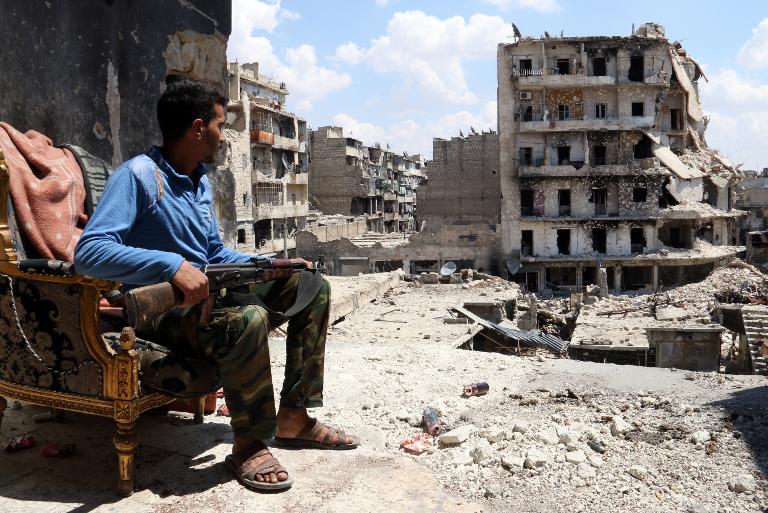 Một phiến quân đang ngồi gác trên tòa nhà giữ một đường phố của thành phố Aleppo ở Syria
