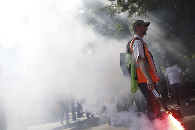 Một công nhân đường sắt Pháp SNCF cầm pháo sáng trong cuộc biểu tình  ở Paris phản đối kế hoạch cải cách của chính phủ Pháp