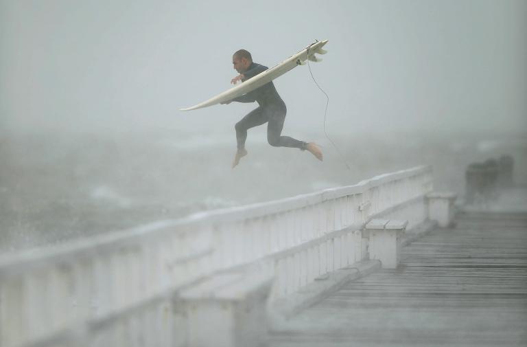 Một người lướt ván nhảy xuống từ cầu tàu vào Vịnh Port Phillip, Melbourne để tận dụng lợi thế của những con sóng