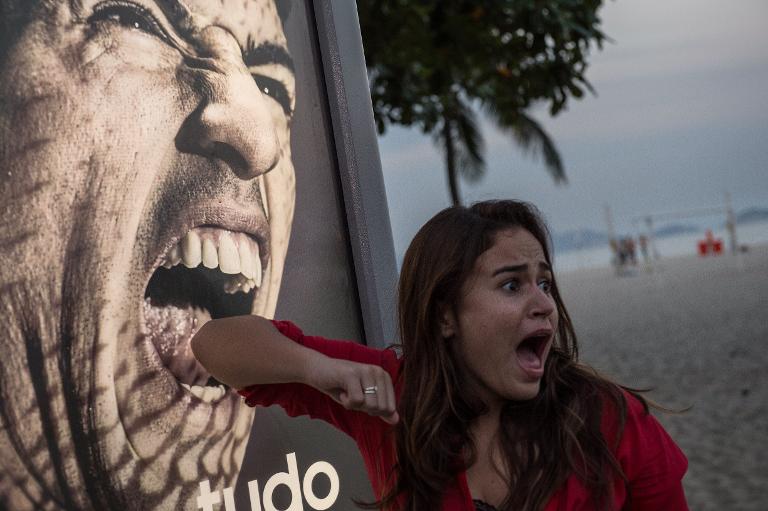 Một khách du lịch thích thú tạo dáng trước bức ảnh Luis Suarez trên bãi biển Copacabana ở Rio de Janeiro, Brazil
