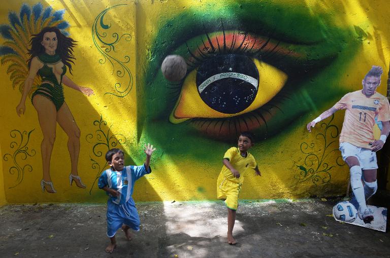 Trẻ em Ấn Độ mang trang phục bóng đá Brazil và Argentina chơi phía bóng trước bức hình Graffit lớn ở Kolkata, Ấn Độ