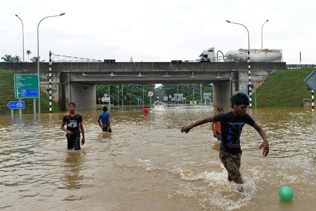 Những đứa trẻ người Sri Lanka chơi bóng trên đường cao tốc bị ngập lụt ở Welipanna