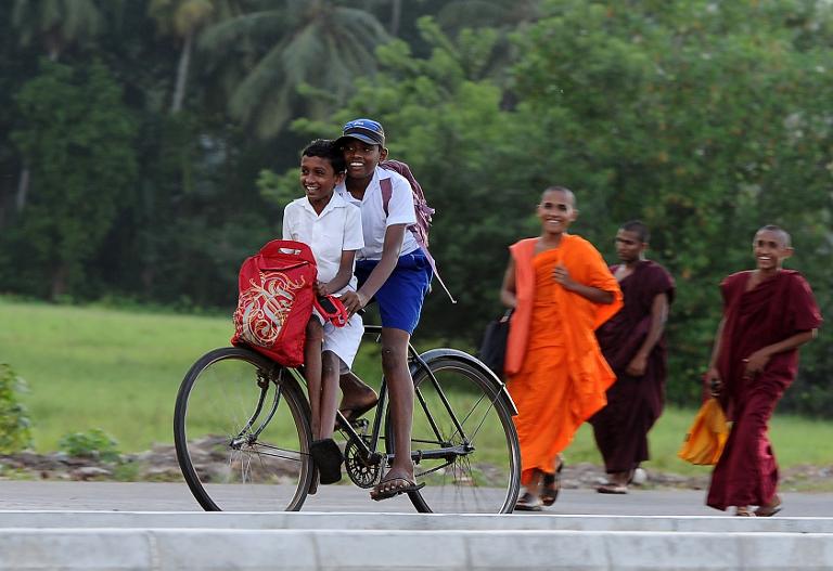 Hai học sinh người Srilanka đi xe đạp vượt qua các nhà sư Piliyandala. Ảnh chụp ở ngoại ô Colombo