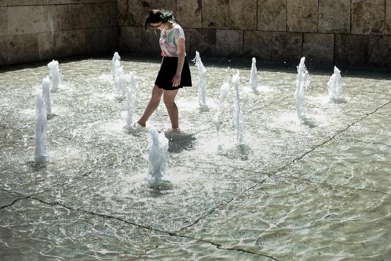 Một cô gái chơi với những vòi nước trong một đài phun nước ở trung tâm Rome, Italia trong một ngày nắng nóng
