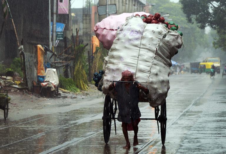 Người đan ông Ấn Độ kéo chiếc xe kéo chất đầy hàng hóa trong một mưa lớn ở Kolkata, thủ phủ bang Tây Bengal, Ấn Độ