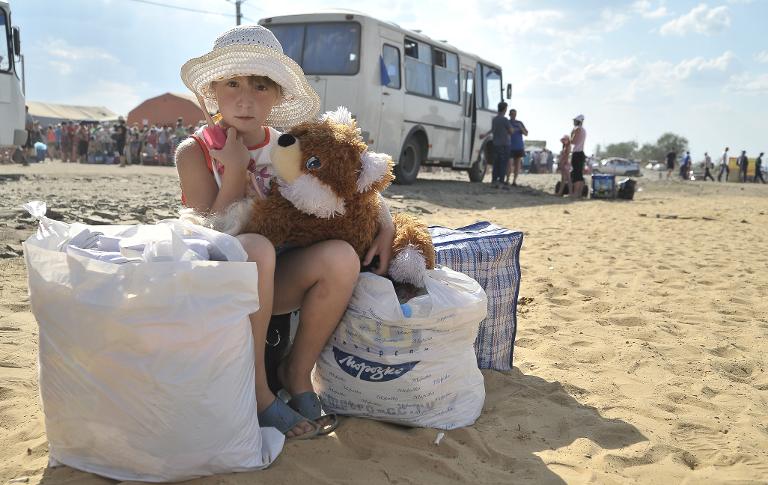 Một cô bé ở miền đông nam Ukraine ôm chú gấu bông của mình chờ đợi được chuyển đến trại tị nạn của thành phố Donetsk