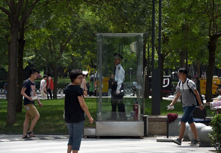 Một nhân viên bảo vệ công viên ở Trung Quốc đứng trong lồng kính có lắp điều hòa để tránh cái nóng ở ngưỡng 30-40 độ C