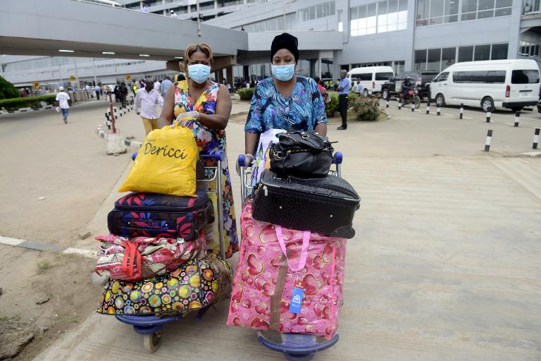 Hành khách mang mặt nạ bảo hộ và găng tay khi đẩy hành lý cá nhân tại sân bay Murtala Mohammed ở Lagos, Nigieria, nơi vừa xác nhận có thêm 1 người mới mắc bệnh Ebola