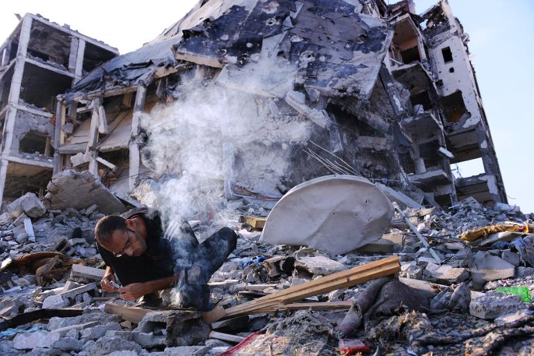 Người đàn ông Palestine nhóm lửa phục vụ sinh hoạt ngay trên đống đổ nát của một căn hộ bị phá hủy do đụng độ giữa Israel và Hamas tại khu vực Dải Gaza