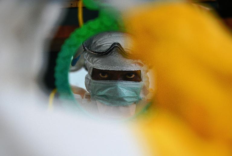 Một nhân viên y tế kiểm tra quần áo bảo hộ của họ trước gương tại một cơ sở MSF ở Kailahun