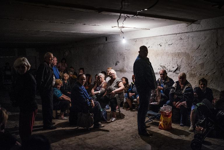 Người dân ngồi bên trong một hầm trú bom tạm thời tại thị trấn Makiyivka, Ukraina