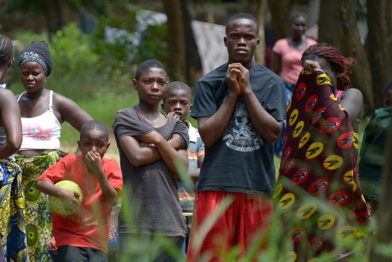 Những người dân Liberia nhìn theo các nhân viên y tế Chữ thập đỏ ở ngoại ô Monrovia đang di chuyển thi thể người hàng xóm tử vong vì Ebola