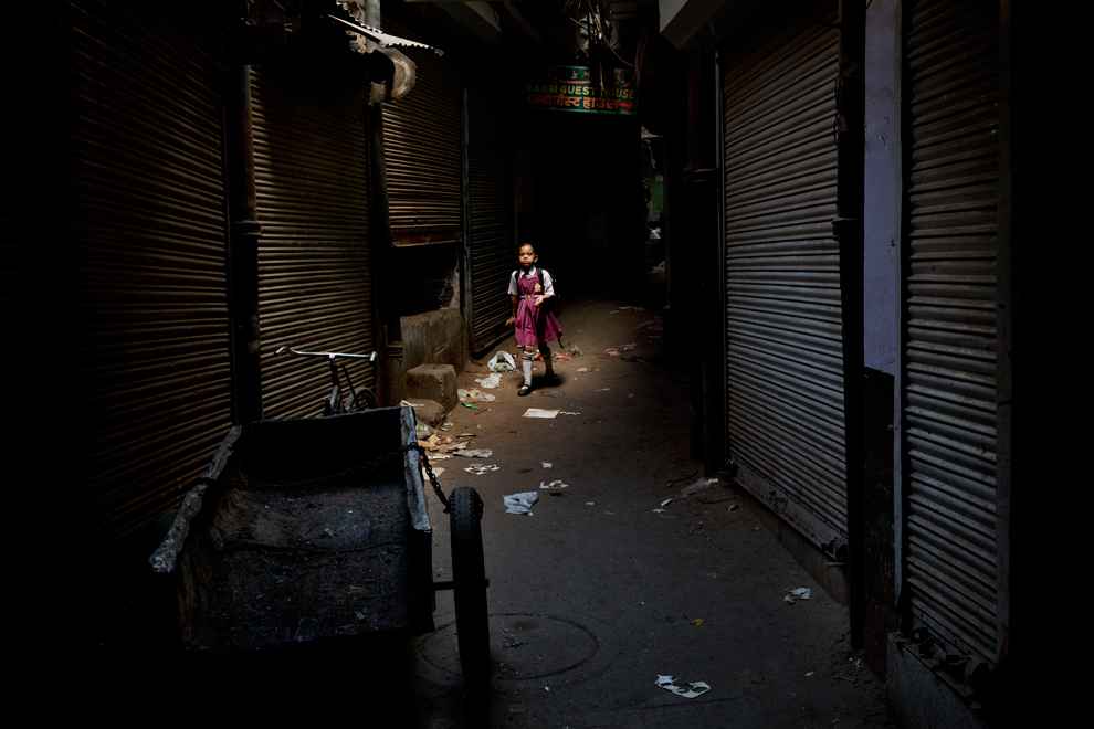 Một bé gái Ấn Độ đi bộ trong một con hẻm ở New Delhi