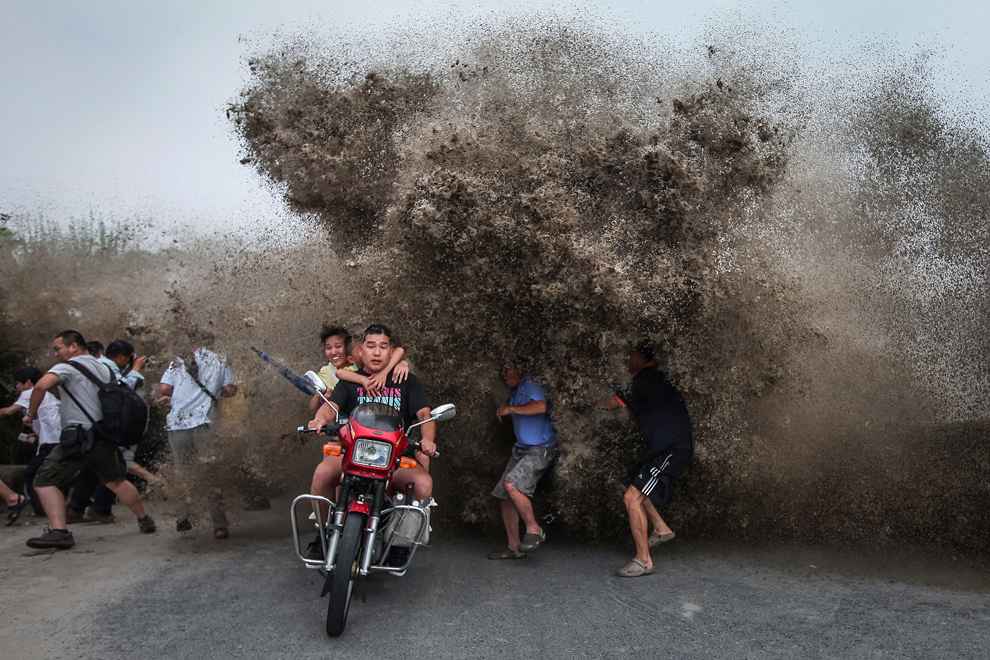 Người đi mô tô và đi bộ tập trung xem thuỷ triều lớn ở bờ sông Qiantang phải bỏ chạy khi con sóng đánh tràn bờ. Đây là một nơi rất thu hút khách du lịch ở Hangzhou, Trung Quốc.