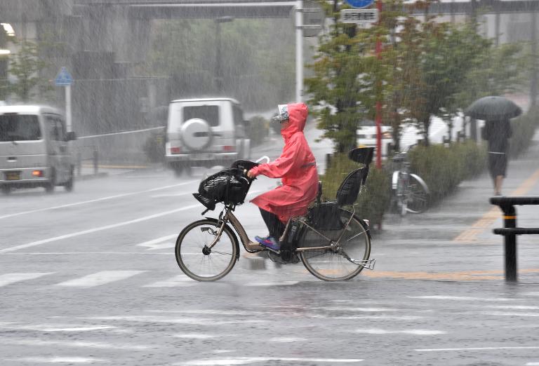 Một người đạp xe đạp giữa cơn mưa lớn do cơn bão Phanfone ở Nhật Bản