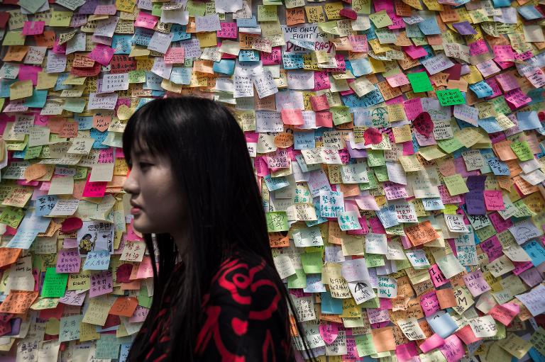Một người phụ nữ đi ngang qua bức tường dán đầy những mảnh giấy ghi thông điệp của người biểu tinh HongKong
