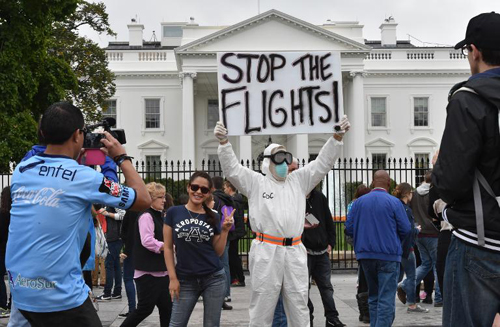Một người đàn ông mặc đồ bảo hộ đứng bên ngoài Nhà Trắng ở Washington, DC với tấm biển yêu cầu dừng tất cả những chuyến bay đến từ Tây Phi