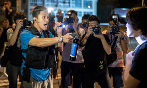 Một nhân viên cảnh sát đe dọa xịt hơi cay vào người biểu tình khi người này đang cố chiếm giữ 1 con đường chính tại Hồng Kông