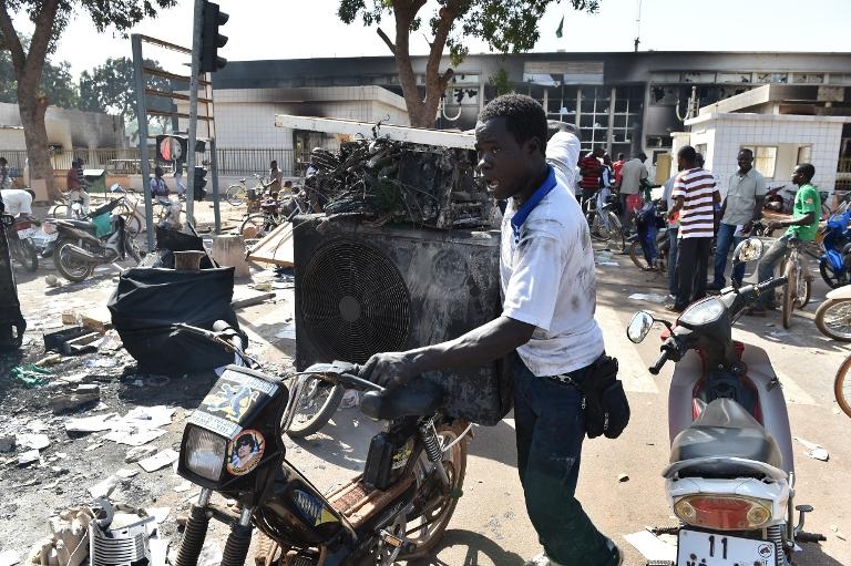 Người đàn ông bên những đồ vật còn dùng được lấy từ tòa nhà quốc hội bị cháy ở Ouagadougou, Burkina Faso