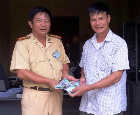 Đại diện tổ công tác Đội CSGT số 3                   trao trả chiếc ví cho ông Hoàng Đình Hải