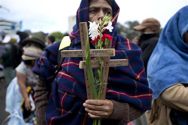 Một người đàn ông bản địa cầm trên tay cây Thánh giá gỗ và những bông hoa tham gia một cuộc biểu tình đòi nhân quyền ở Guatemala, 25/02/2016.