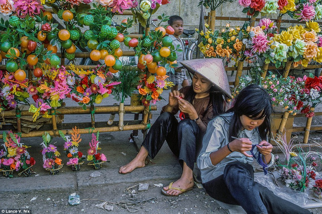 Những cô gái vừa bán hoa vừa tranh thủ đan lát trong khu chợ Mỹ Tho, đồng bằng sông Cửu Long năm 1969.