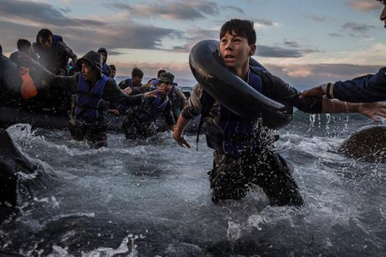Hàng trăm người di cư từ Thổ Nhĩ Kỳ mừng rỡ khi đặt chân tới đảo Lesbos của Hy Lạp sau chuyến hành trình dài chống chọi với biển động và gió lớn.