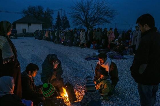 Một gia đình người tị nạn từ Syria sưởi ấm quanh đống lửa trong khi những người khác xếp hàng đăng ký tại một trại tiếp nhận ở Gevgelija, Macedonia, ngày 21/11/2015.