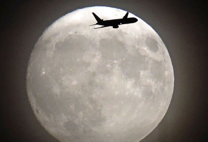 Chiếc máy bay cất cánh từ sân bay Heathrow, London trên nền Siêu Trăng. (ảnh: AP)
