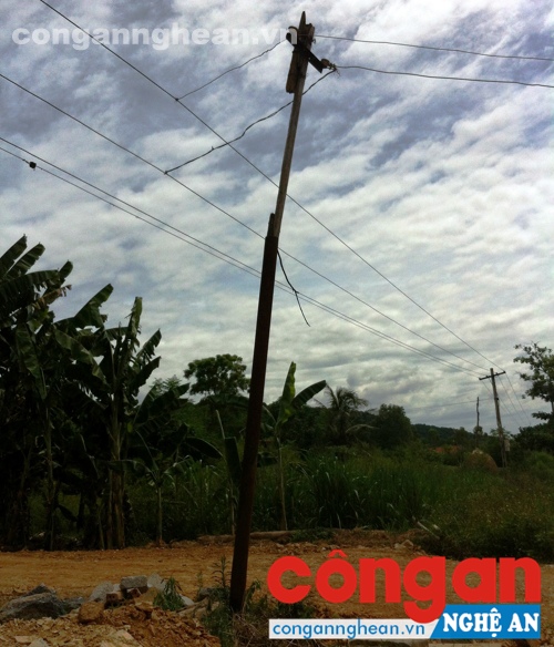 Một cây cột điện bằng sắt với đường dây điện trần được móc nối tạm bợ dẫn vào hai xóm của xã Nghĩa Hội