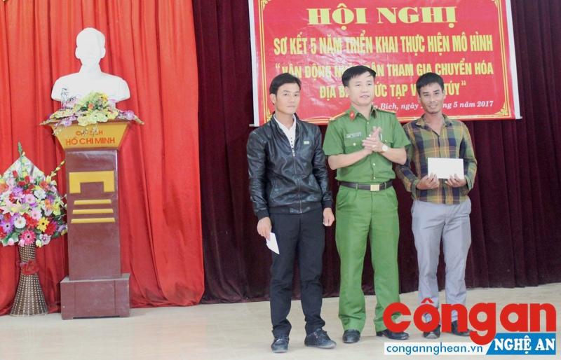 Anh Nguyễn Hữu Đạt (bên trái) được Trung tá Nguyễn Duy Thanh, Trưởng Công an huyện Diễn Châu tặng quà tại Hội nghị sơ kết mô hình “Vận động nhân dân tham gia xóa địa bàn phức tạp về ma túy”