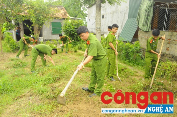 Các CBCS Công an huyện Thanh Chương đang dọn cỏ trong vườn chị Nguyễn Thị Xuân - thân nhân liệt sĩ ở khối 13, thị trấn Dùng