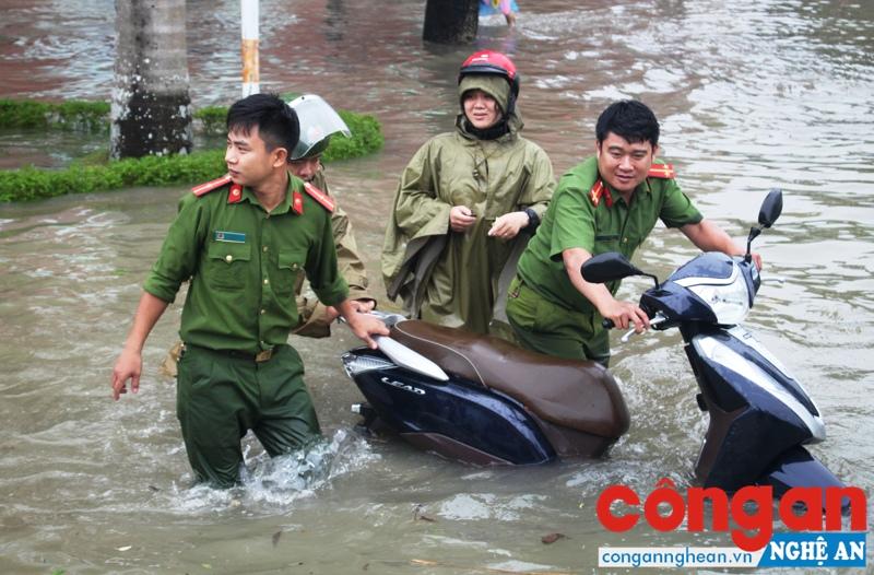 Lực lượng Cảnh sát Trật tự giúp người dân di chuyển phương tiện qua vùng ngập lụt - Ảnh: Xuân Bắc