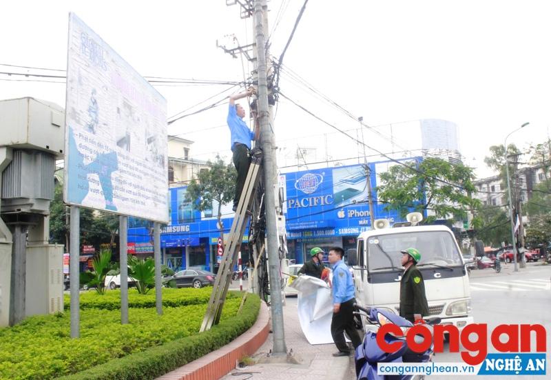 Lực lượng quản lý trật tự đô thị tháo gỡ các biển quảng cáo sai quy định tại đoạn giao nhau đường Nguyễn Thị Minh Khai và Lê Hồng Phong (TP Vinh)