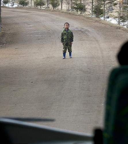 Hình ảnh một bé trai Triều Tiên đứng ngay trên đường khi chiếc xe bus chở nhiếp ảnh gia Lafforgue đi bên trong địa danh Samijyon.